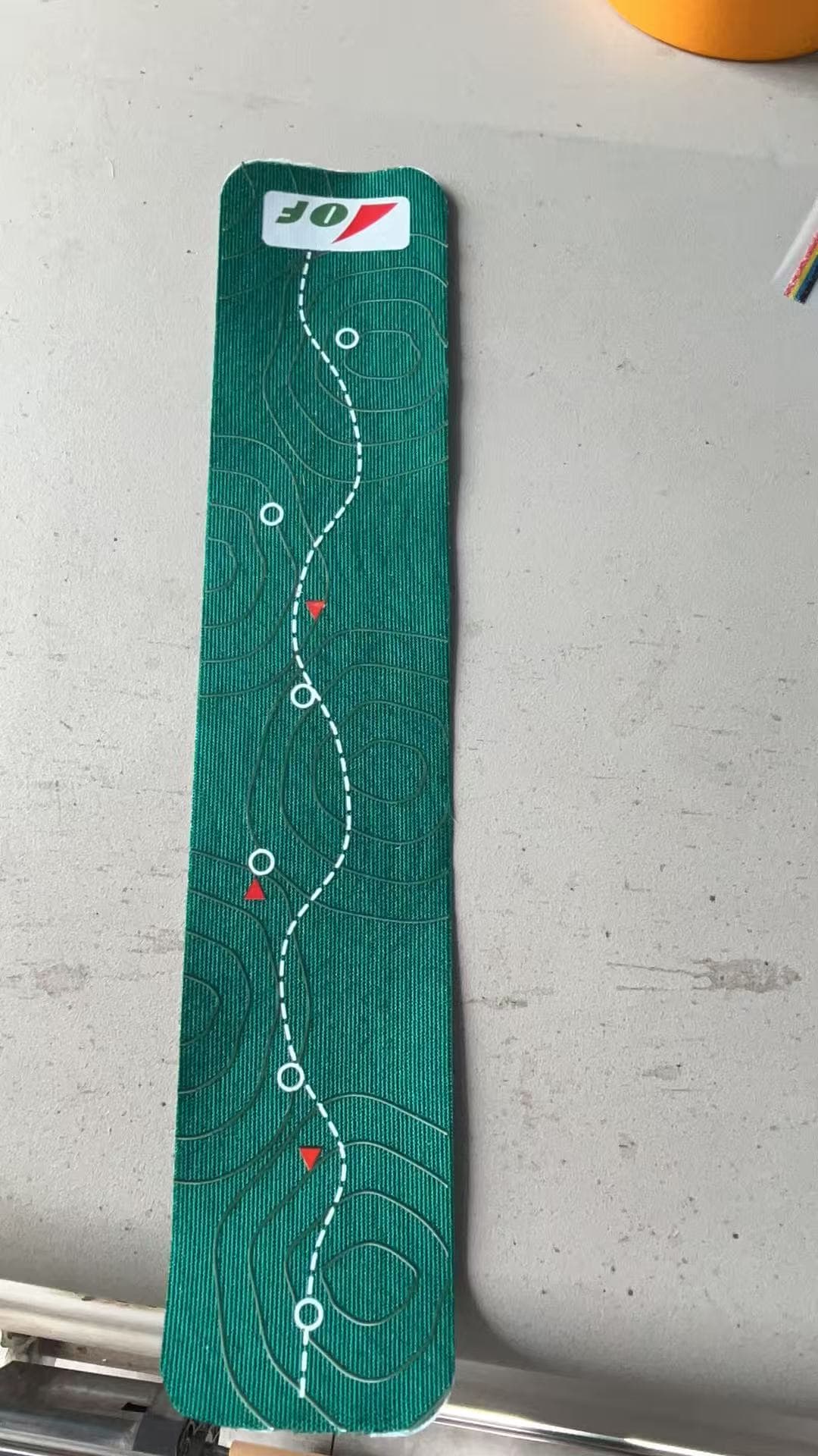 Actual green Wild Geometry kinesiology tape with contour lines and route markings on a tabletop